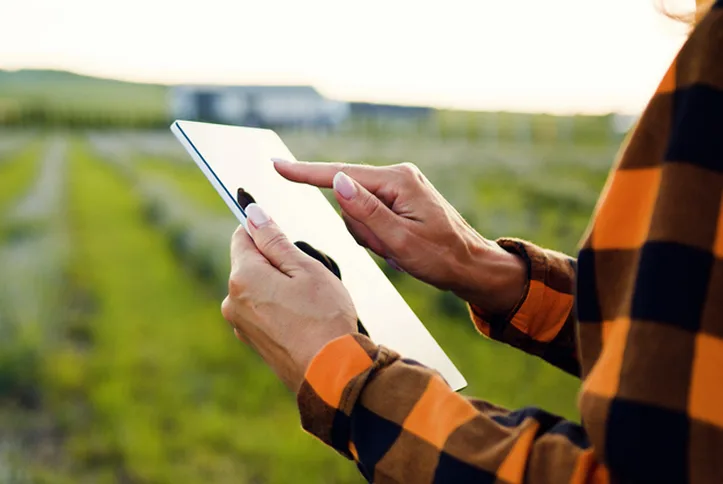Agricultora gestionando cultivos con una tableta digital en el campo, aplicando tecnología para la administración agrícola